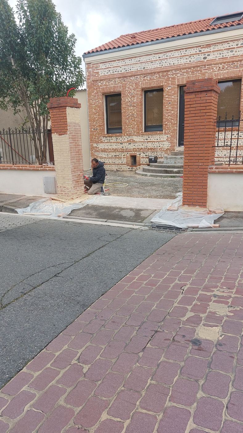 Artisan RGBAT réalisant la finition d'un pilier de portail en brique